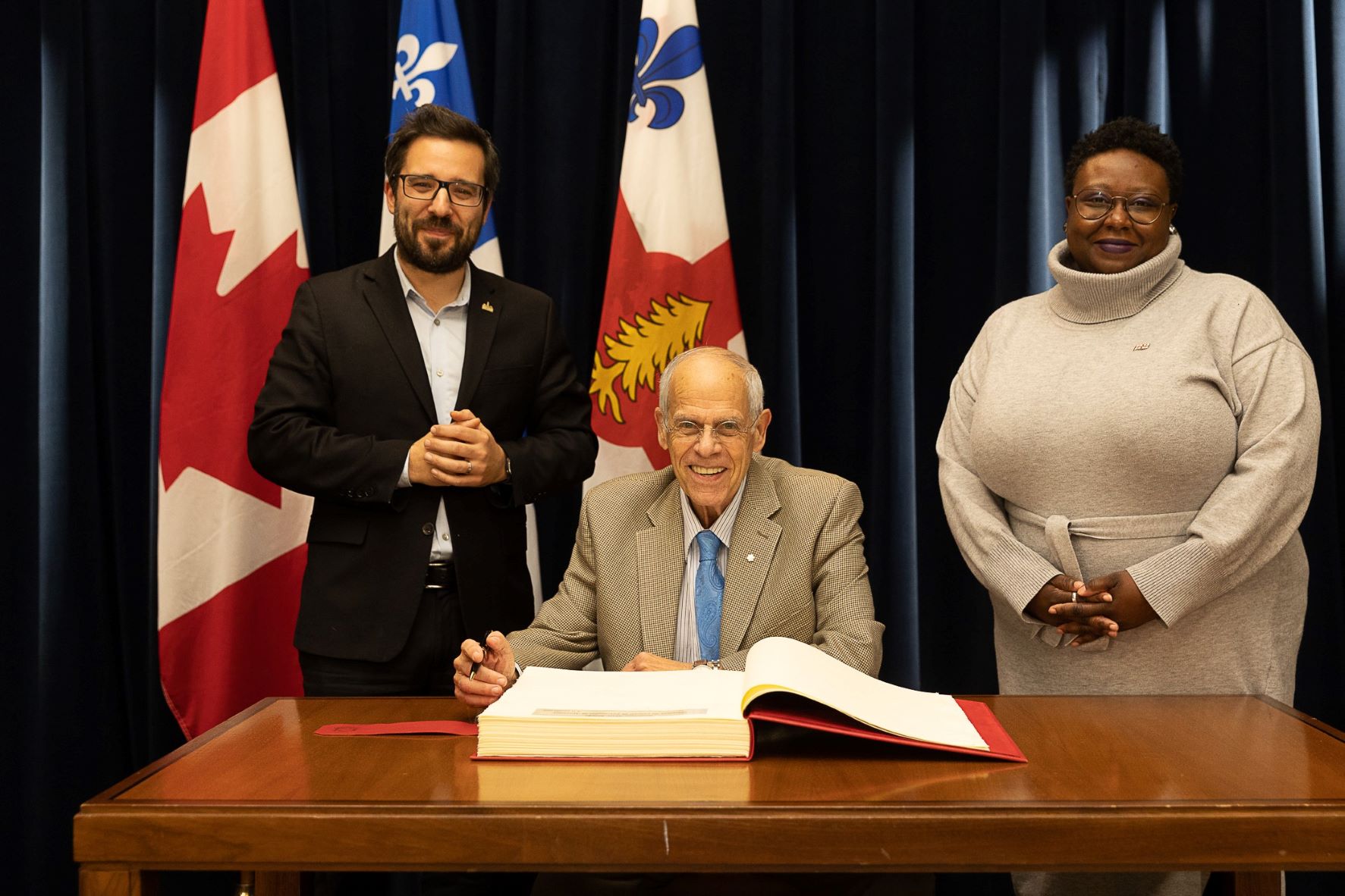 M. Peter Jacobs signant le livre d'or de la Ville accompagné de M. Robert Beaudry et de Mme Ericka Alneus (photo : Ville de Montréal / Bianca Diorio)